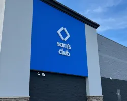 Exterior of a Sam's Club store with a large blue sign and clear sky background