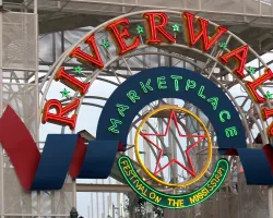 Colorful neon sign archway reading Riverwalk Marketplace Festival on the Mississippi with star and decorative elements.