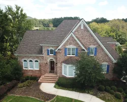 a large brick house with blue shutters and a driveway