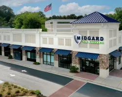 Exterior view of Midgard Self Storage facility with blue awnings and American flag flying above on a clear day