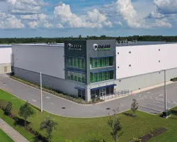 Modern Midgard Self Storage facility with green windows, spacious parking, and clear blue skies above.