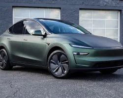 Matte green electric SUV parked in front of modern garage doors with sleek aerodynamic design.