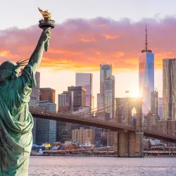 a statue of a person holding a torch in front of a city