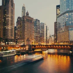 a river with a bridge and tall buildings in the background