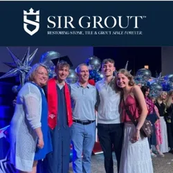 Group of smiling people posing at a celebration event with Sir Grout logo and balloons in background.