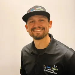 Smiling man wearing a Roof it Forward cap and black polo shirt benefitting children's health care.