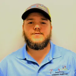 Man with beard wearing a blue shirt and cap with Roof It Forward logo supporting Children's Health Care