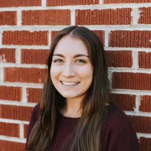 a woman standing in front of a brick wall