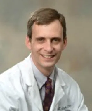 a man wearing glasses and smiling at the camera.