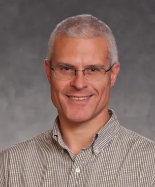 a man wearing glasses and looking at the camera.