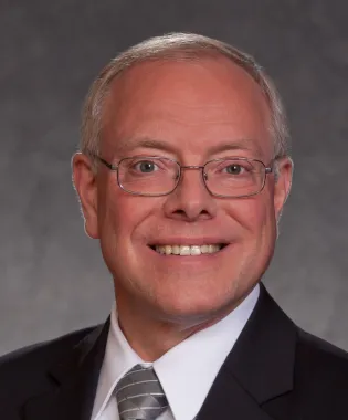 a man wearing a suit and tie smiling at the camera.