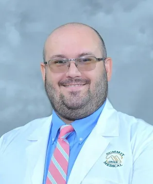 a man wearing glasses and smiling at the camera.