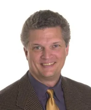 a man wearing a suit and tie smiling at the camera.