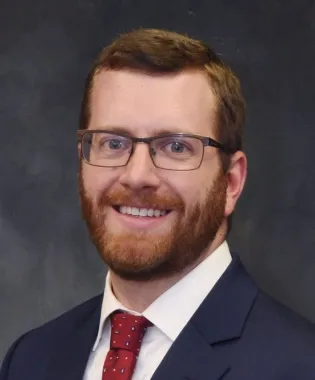 a man wearing glasses and smiling at the camera.