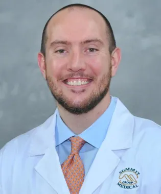 a man wearing a suit and tie smiling at the camera.