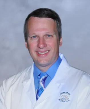 a man wearing a suit and tie smiling at the camera.
