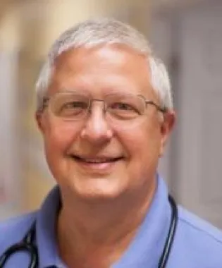 a man wearing glasses and smiling at the camera.