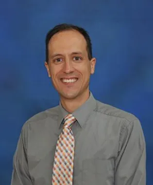 a man wearing a suit and tie smiling at the camera.