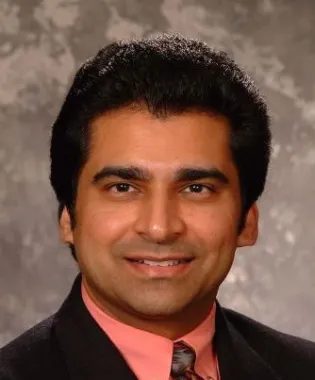 Vijay Antony wearing a suit and tie smiling at the camera.