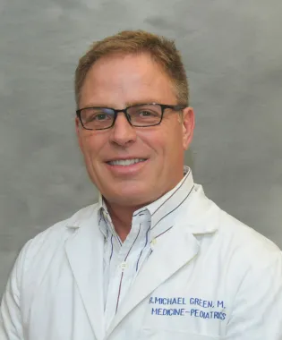 a man wearing glasses and smiling at the camera.