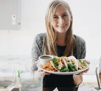 a woman sitting at a table with a plate of food