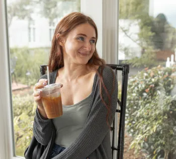 a woman sitting on a chair holding a drink and smiling