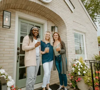 a group of women posing for a picture outside of a house