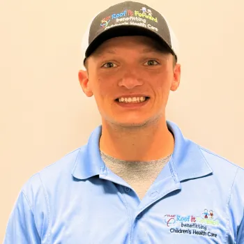 Smiling man wearing a blue shirt and cap promoting Roof It Forward benefiting Children's Health Care.