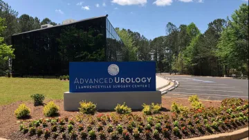 Sign for Advanced Urology at Lawrenceville Surgery Center surrounded by greenery and flowers.
