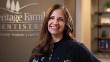 a woman smiling in front of a sign