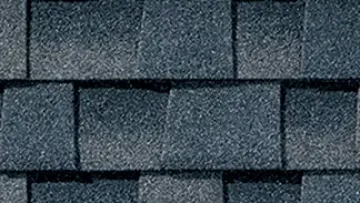 Gray asphalt shingle roofing on a modern suburban house with close-up texture on the side