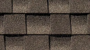 Modern suburban house with brown architectural shingle roof and stone accents on the exterior walls.