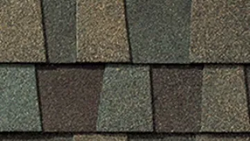 Large beige two-story house with green lawn and detailed asphalt shingle roof showcasing roofing material close-up