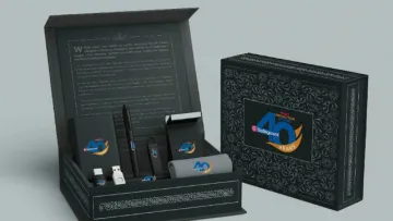 Black gift box set with branded 40th anniversary items including USB, pen, and towel with ornate patterns