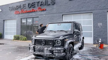 Black Mercedes SUV covered in soap being washed outside Simple Details Elite Automotive Care shop.