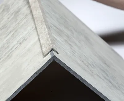 Close-up of a corner joint showing light gray wood panels secured with a metal bracket.