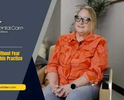 Smiling woman in orange shirt shares positive dental care experience at Advanced Dental Care clinic.