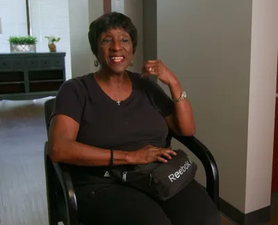 Smiling woman sitting in a chair in a modern dental office with a Reebok fanny pack on her lap.