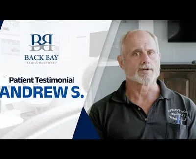 Middle-aged man giving a patient testimonial for Back Bay Family Dentistry with dental office background.