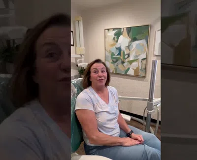 Woman sitting in a dental chair with abstract painting on wall in a modern clinic setting