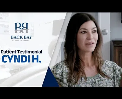 Woman sharing her patient testimonial for Back Bay Family Dentistry with logo and text on screen.