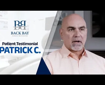 Middle-aged man giving a patient testimonial for Back Bay Family Dentistry in a professional setting.