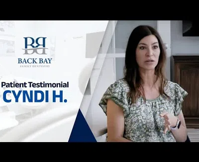 Woman giving a patient testimonial for Back Bay Family Dentistry in a calm indoor setting.