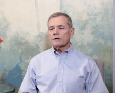 Two women exchanging a document across an office desk with decorative circular wall art in the background