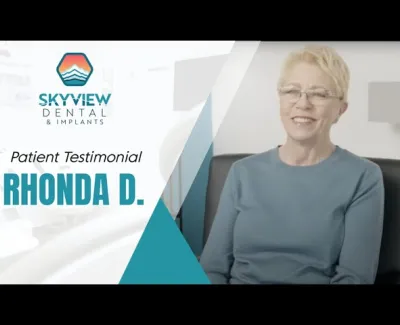 Happy woman giving a patient testimonial for Skyview Dental and Implants in a bright dental office.