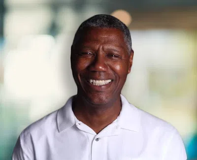 Smiling middle-aged African American man wearing a white polo shirt with blurred background