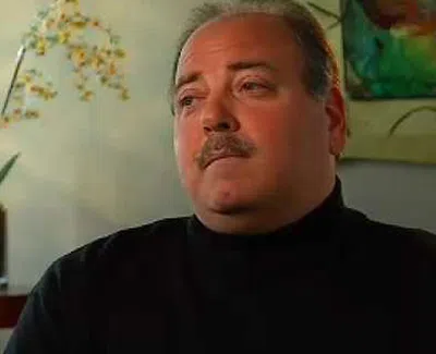 Portrait of a middle-aged man with mustache wearing a black turtleneck, looking to the side indoors