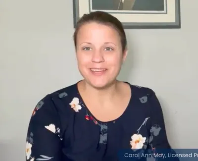 Smiling female licensed professional counselor in floral top sitting indoors with Ascend Medical logo in background.