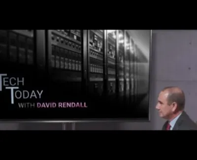 Man in suit watching Tech Today with David Rendall episode featuring server racks on screen.