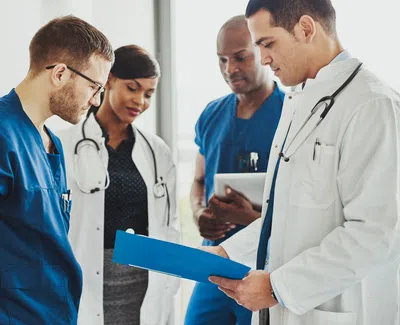 A team of diverse doctors and nurses reviewing patient charts during a medical meeting in a hospital.